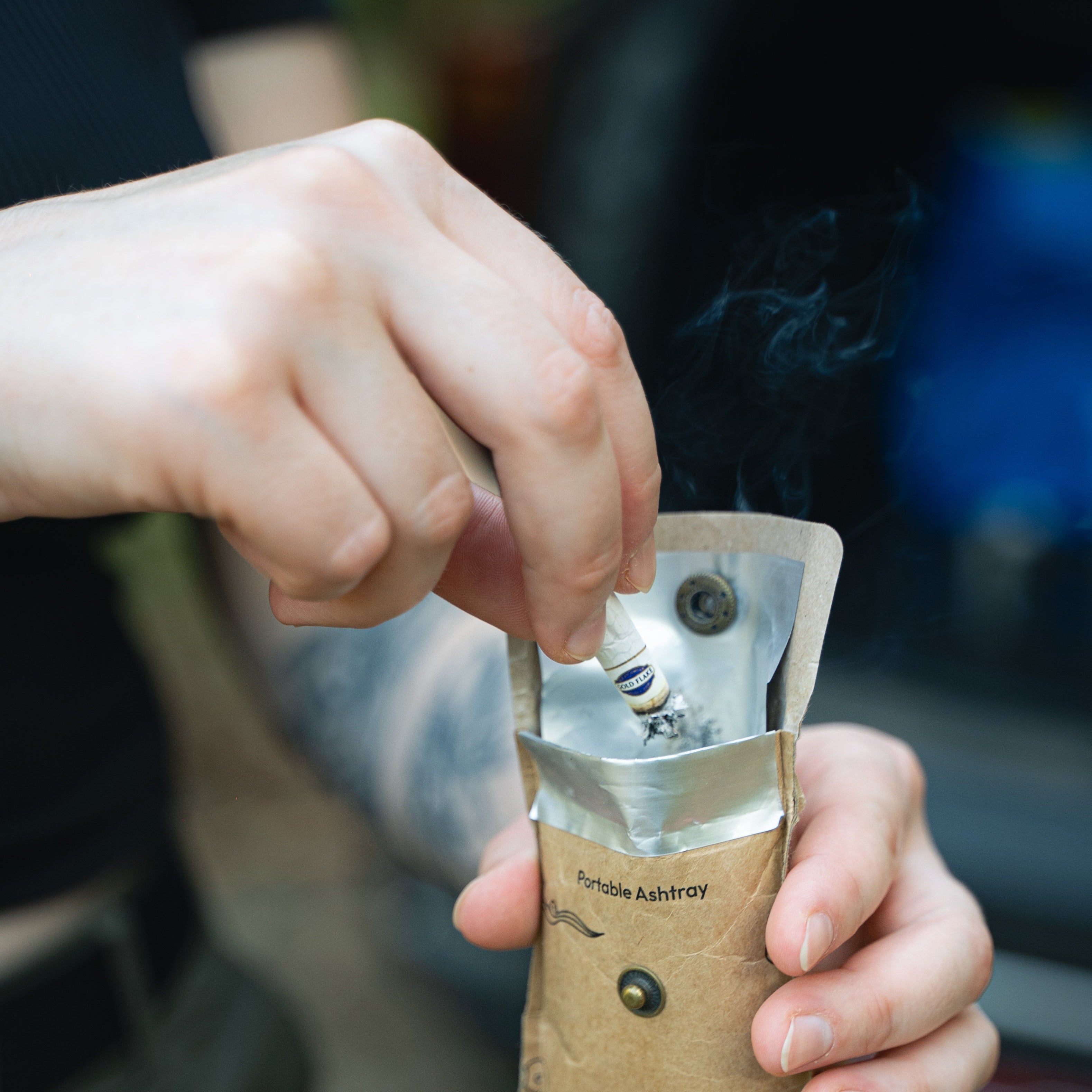 Person holding a Stubb pocket ashtray with a blurred background